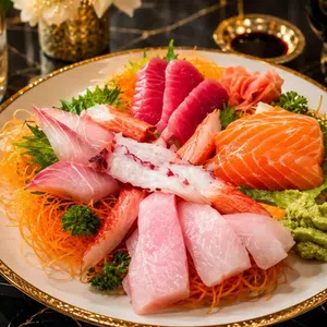 Assorted sashimi plate with salmon, tuna, white fish, crab, wasabi, and garnishes on a decorative plate.