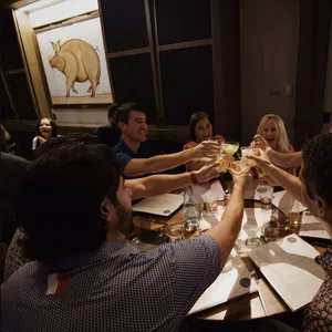 Group of friends raising glasses for a toast around a restaurant table with menus and drinks.