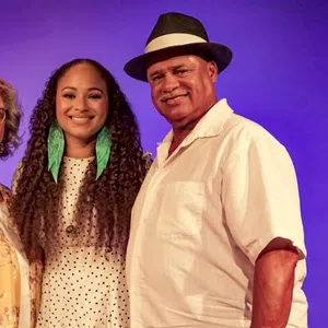 Smiling three generations family portrait with purple background and casual summer clothing