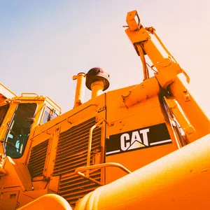 Close-up of a yellow Caterpillar bulldozer with visible CAT logo under bright sunlight.