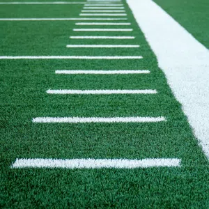 Close-up of green turf with white yard lines on an American football field.