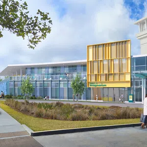 Modern imaging center with glass facade, yellow accent panels, landscaped front, and people walking outside.