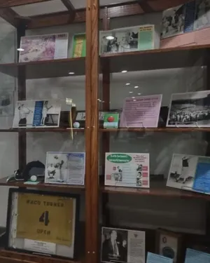 Wooden display case with historical sports memorabilia including photos, cards, and a framed Waco Turner jersey.