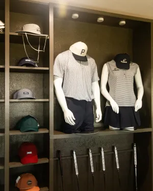 Golf apparel and caps displayed on shelves with mannequins wearing golf outfits and golf clubs below.