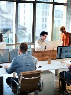 a group of people sitting around a table with computers