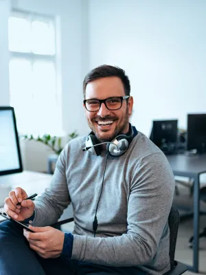 a man sitting at a desk with a computer and headphones on