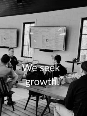 Black and white image of a business meeting with four people discussing growth strategies in a modern office.