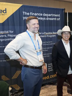 Two men standing and smiling at a business expo booth with finance and firestop promotional banners.