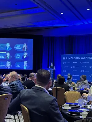 SFR Industry Awards event with attendees seated at round tables, presenter at podium, and judging panel on screen.