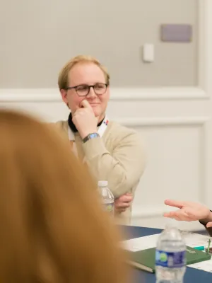 Diverse group in business casual attire engaged in a lively discussion around a conference table.