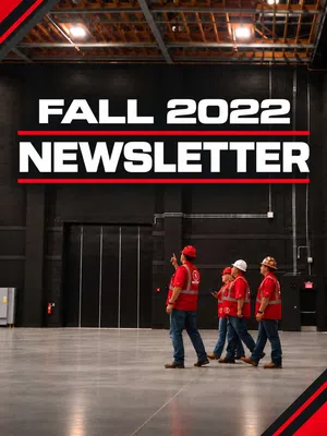 Workers in red safety vests and helmets walk in a large industrial space under Fall 2022 Newsletter text.