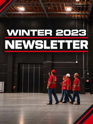 Four construction workers in red safety gear walk inside a spacious industrial building with Winter 2023 Newsletter text above.