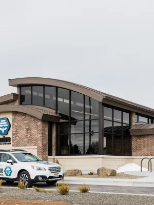 Modern Beehive Federal Credit Union building with branded vehicle and American flag outside on overcast day