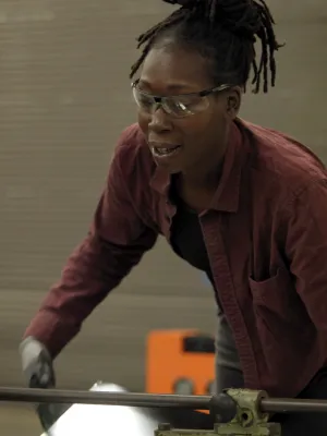 Woman wearing safety glasses operating industrial machinery in a workshop