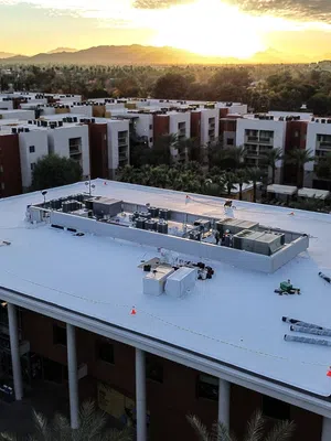 Mattco crew installing white single-ply roof on university area student housing building in Arizona at sunset
