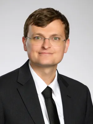 Gavin ratcliffe wearing glasses and a suit