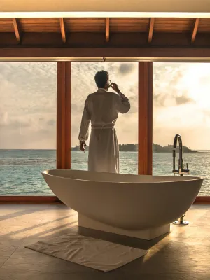 a person in a white robe standing next to a bathtub