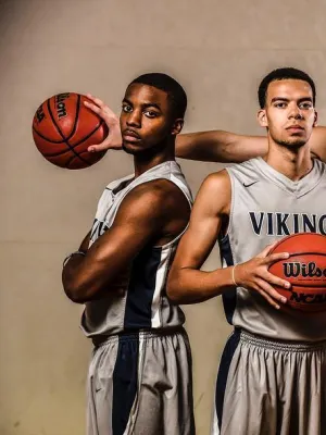 Five male basketball players wearing Vikings uniforms posing confidently with basketballs in a gym setting.