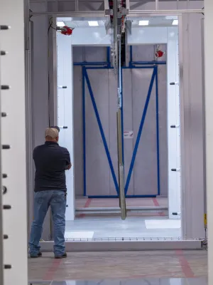 Man standing in a large industrial facility observing machinery and equipment in a spacious warehouse area.