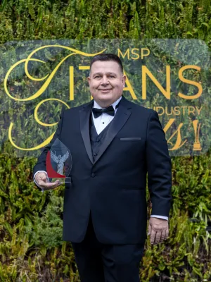 a man in a suit holding a trophy in front of a sign