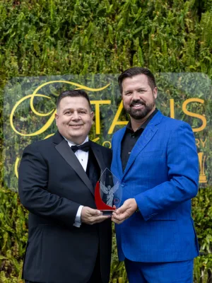 a person in a suit and a person in a suit holding a trophy