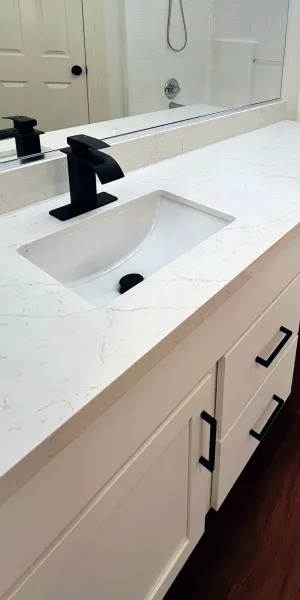 Modern white bathroom vanity with black faucet, rectangular sink, large mirror, and dark wood flooring.