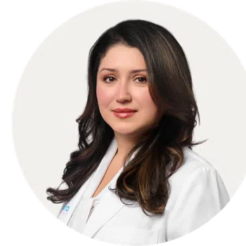 Professional woman with long dark hair wearing a white lab coat against a light background.