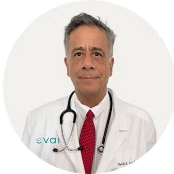 Middle-aged male doctor in white coat with stethoscope and red tie, looking at camera on white background.