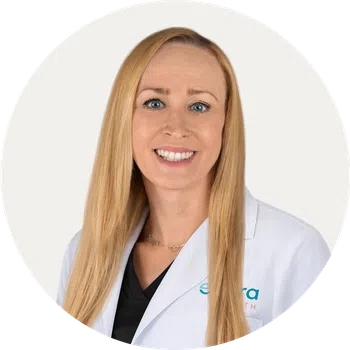 Smiling female healthcare professional with long blonde hair wearing a white lab coat on white background