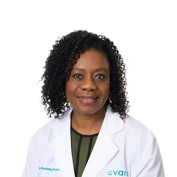 Smiling female pharmacist with curly hair wearing a white lab coat against a white background
