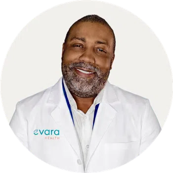Smiling doctor in white coat with Evara Health logo on blue circular background.