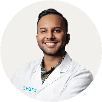 Smiling male healthcare professional wearing a white lab coat with evara health logo on a white background