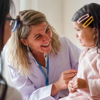 Smiling female doctor interacts with young girl patient during a friendly medical check-up in clinic.