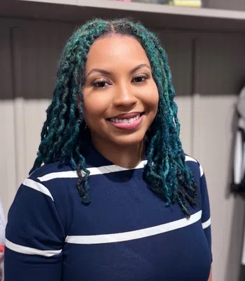 Smiling woman wearing a navy blue and white striped shirt standing indoors.