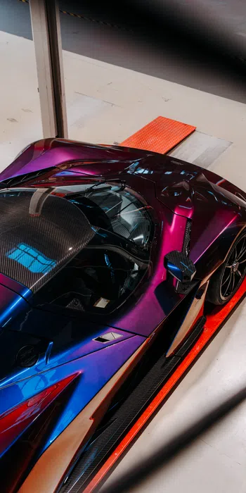 Top view of a sleek purple and blue sports car on a red platform with carbon fiber roof and black rims.