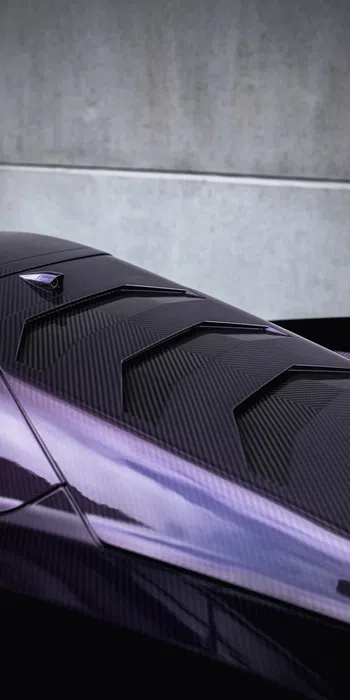 Close-up of a sleek purple and black carbon fiber car hood with aerodynamic vents and sharp lines.