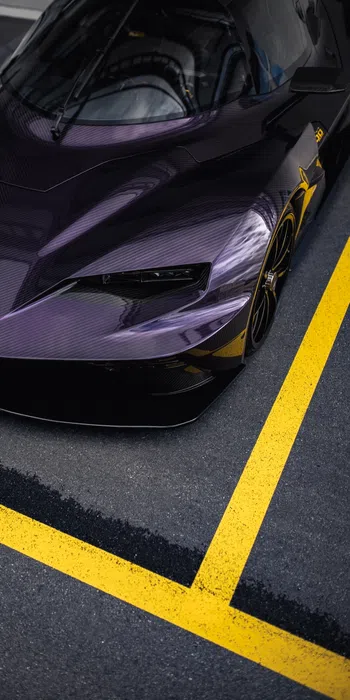 Close-up of a sleek purple KTM sports car parked in a lot with bright yellow parking lines.