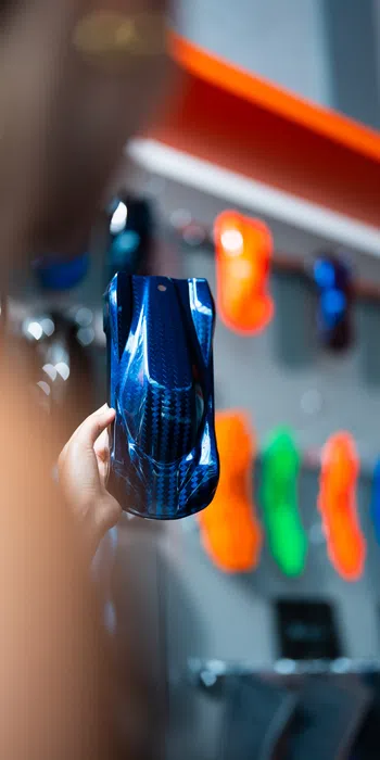 Person holding a sleek blue remote control car shell with colorful RC car bodies on display in the background.