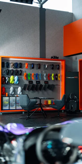 Showroom display of colorful motorcycle parts and accessories with black chairs and orange shelving units.
