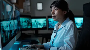 a person sitting at a desk with a computer with cctv targeting security