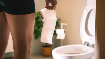 a person's hand holding a towel over a toilet