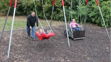 a person and two children on a swing set