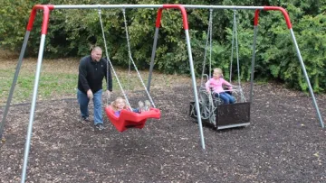 a person and two children on a swing set