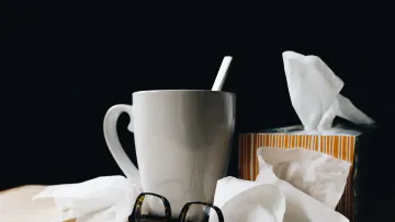 a white mug with a straw and glasses on a table