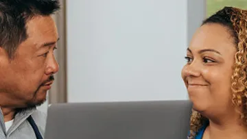 a man and a woman looking at a laptop