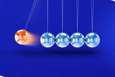 Orange metal sphere striking silver spheres in a Newton's cradle on a blue background.