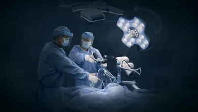 Surgeons using robotic-assisted technology for precision surgery under bright operating room lights.