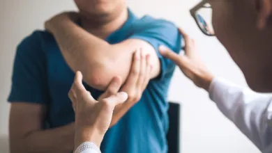 Doctor examining and treating patient’s elbow pain during a medical consultation in clinic.