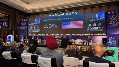 Audience watching IAACON 2025 conference with large screen showing arthritis statistics and American flag