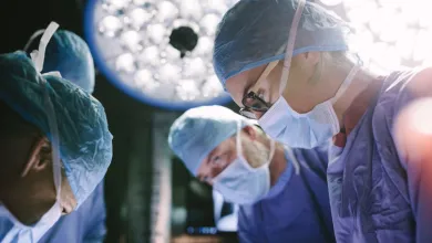 Medical team wearing surgical masks and scrubs focused during an operation under bright operating room lights